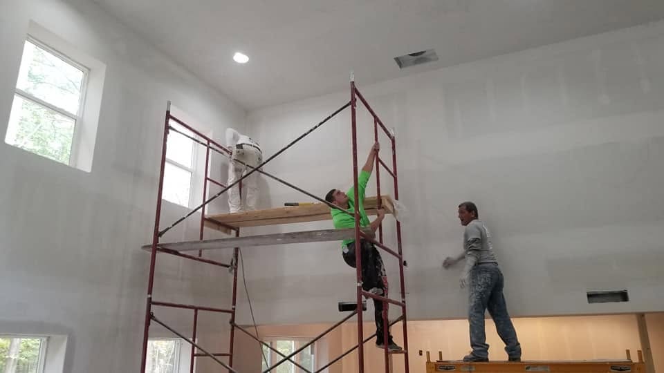 Drywall finishing on scaffolding — high wall